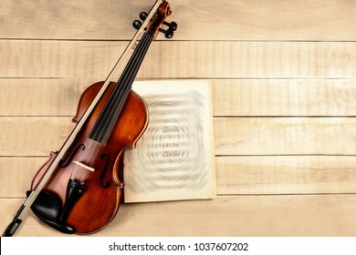 violin bow sheet of paper with notes on a wooden table