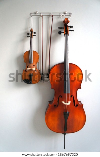 Violin and cello hanging on wall. Duets string\
instrument 