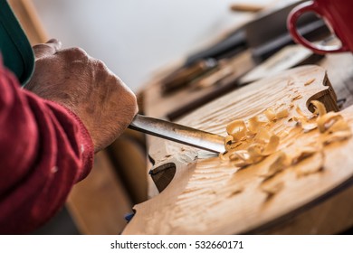 violin maker carving with a chisel on a violin body - Powered by Shutterstock