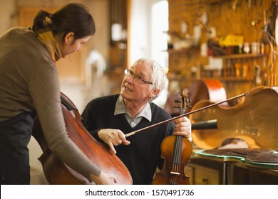 Violin makers discussing instruments in workshop - Powered by Shutterstock