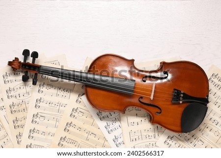 Violin and music sheets on white wooden table, top view. Space for text