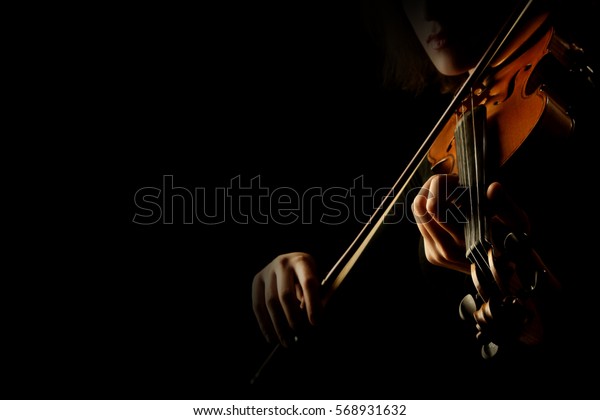 Violin player hands. Violinist\
playing violin isolated on black. Close up of musical\
instruments