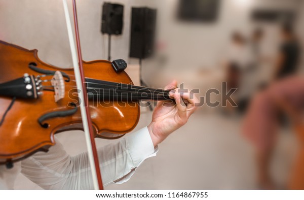 Violin playing viola musician. Man violinist classical\
musical instrument  fiddle playing on wedding.\
 Close up young\
fiddler dressed elegantly playing on wooden violin orchestra .\
Blurred soft focus 