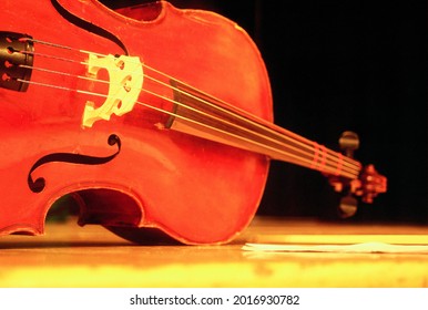 Violin Rests On Its Side On A Stage Floor Against A Black Background - Front Angle, Saturated Color, Horizontal, No People