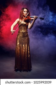 Violinist girl performs on stage. Stage light.