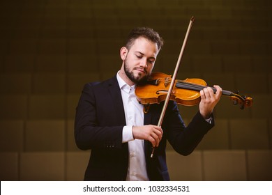 Violinist. Image of a man violinist in a concert hall. The young violinist wears a suit.