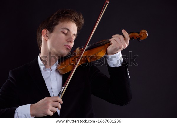 A violinist plays the violin in a Symphony\
orchestra concert, a musician emotionally plays classical music on\
a wooden instrument