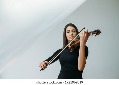 Violinist woman. Online education. Distance lesson. Lockdown reality. Inspired lady enjoying playing violin closed eyes with transparent plastic film under head isolated neutral copy space.