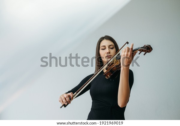 Violinist woman. Online education. Distance\
lesson. Lockdown reality. Inspired lady enjoying playing violin\
closed eyes with transparent plastic film under head isolated\
neutral copy space.