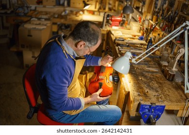 Violinmaker shaping a new violin in a well lit workshop, meticulously examining the instrument under a lamp, surrounded by an array of tools and materials essential for craftsmanship