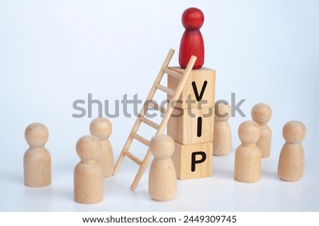 VIP text on wooden cubes with wooden dolls looking up to red figure doll.