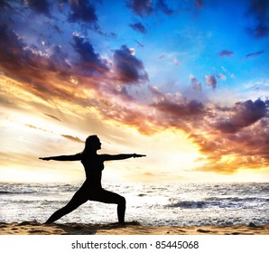 Virabhadrasana II Warrior Pose By Beautiful Woman Silhouette On The Sand Beach And Ocean Nearby At Sunset Background In India, Goa