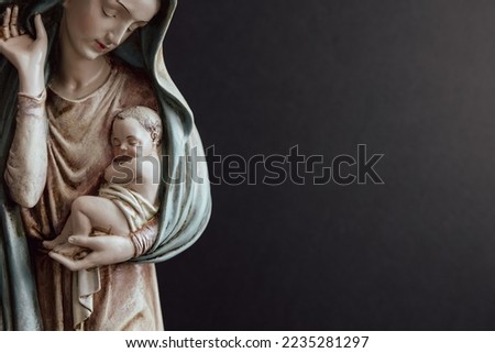 Virgin Mary holding baby Jesus on a black background with copy space