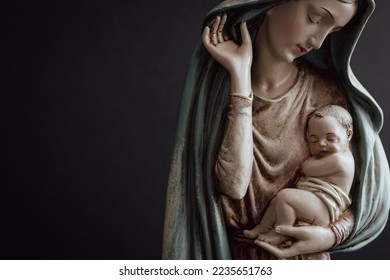 Virgin Mary and infant Jesus in her arms on a black background with copy space 