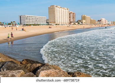VIRGINIA BEACH, VIRGINIA - JULY 13, 2017:  View of boardwalk hotels and people enjoying the beach as seen from the oceanfront jetty.  