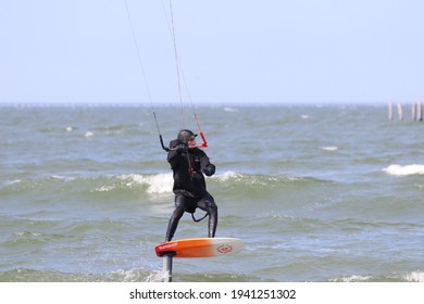 Virginia Beach, Virginia, USA - March 21, 2021: A Kite Boarder Skims Over The Surf Parallel To The Beach.