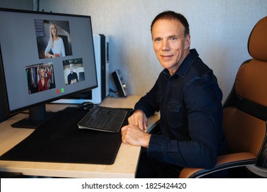 Virtual Business Team Meeting Online At Home. Teleworking Over A Video Call On Computer. Man Sitting At Room Table Having A Video Communications Conference With His Colleagues. Remote Teams Meet