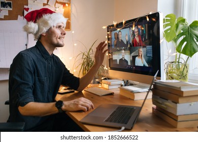 Virtual Christmas Day House Party. Man Smiling Wearing Santa Hat Business Video Conferencing Young Man Having Video Call Via Computer In The Home Office Online Team Gift Opening Conference Calling. 