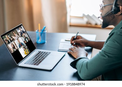 Virtuelle Konferenz mit multiethnischen Menschen. Afroamerikaner im Headset lernt per Laptop und Video-Chat-App remote. Auf dem Laptop-Bildschirm der Lehrer und die Gruppe der verschiedenen Menschen, online