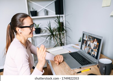 Virtual Conference, Online Meeting. Business Woman Waving Hello To Coworkers On Laptop Screen, She Using Laptop App For Video Call With Several People At Same Time Together. Side View