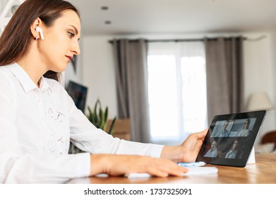 Virtual Conference, Online Meeting With Coworkers, Employees. A Young Woman In Home Office Is Using Tablet For Video Communication With Several People At Same Time Together