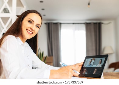 Virtual Conference, Online Meeting With Coworkers, Employees. A Young Woman In Home Office Is Using Tablet For Video Communication With Several People At Same Time Together
