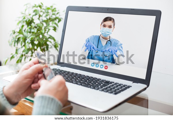 Virtual doctor visit,telemedicine healthcare\
concept,young female doctor giving advice over laptop computer\
screen to elderly woman,hands holding glasses medical worker on\
display,remote\
appointment