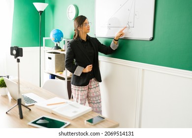 Virtual Education. Hispanic Young Woman Wearing A Blazer And Pajamas While Giving A Math Class 