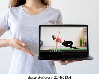 Virtual Fitness Class. Online Training. Pilates Tutorial. Woman Hand Recommending Sport Video Program On Laptop With Athletic Coach Performing Exercise On Screen Isolated On Light.