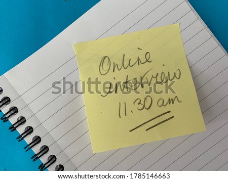 Virtual online interview appointment reminder scribbled on a sticky note and notepad business style