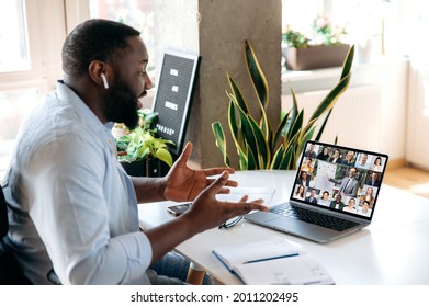 Virtual Online Meeting By Video Call. African American Man Communicating Via Video Conference With Multinational Colleagues, Gesturing With His Hands, While Sitting At Home At Work Place, Distant Work