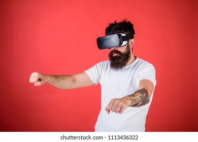 Virtual Racing Concept. Hipster On Confident Face Driving Bike On High Speed In Virtual Reality. Man With Beard In VR Glasses Driving Motorbike, Red Background. Guy Play Racing Game In VR.