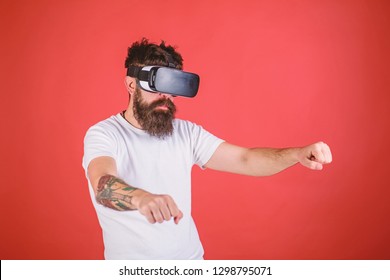 Virtual Racing Concept. Hipster On Confident Face Driving Bike On High Speed In Virtual Reality. Man With Beard In VR Glasses Driving Motorbike, Red Background. Guy Play Racing Game In VR.