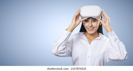 Virtual reality concept: smiled young woman in light shirt with VR glasses on her head on light blue background with place for your logo or text, mockup - Powered by Shutterstock
