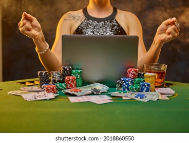 A virtual reality. Gambling. Online casino. A woman sits at a poker table, on which there is a laptop, a lot of chips, cards, bundles of money are laid out. Gambling addiction. Hobby. Hope for victory - Powered by Shutterstock