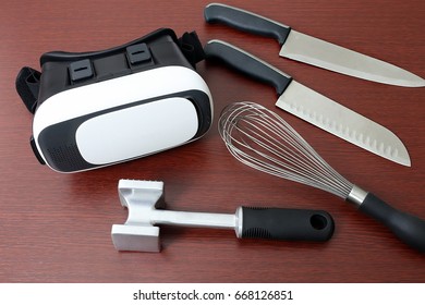 Virtual reality headset goggles laying next to kitchen knives, meat tenderizer, and whisk  - Powered by Shutterstock