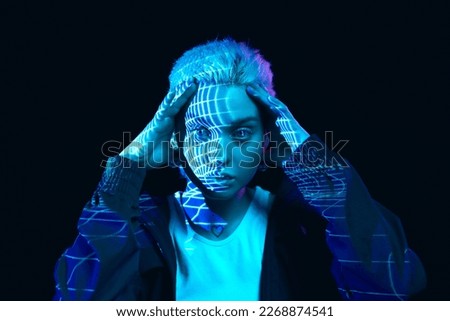 Virtual reality. Portrait of young blonde girl with neon holographic stripes on face posing over dark background in blue neon lights. Concept of art, modern style, cyberpunk, futurism and creativity