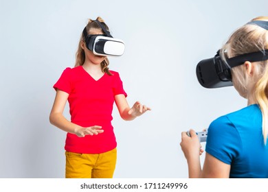 Virtual Reality Simulation. Pair of Funny and Playful Caucasian Twin Teenager Girls Playing With VR (Virtual Reality) Helmets With Joystick Manipulation. Horizontal Image Composition
