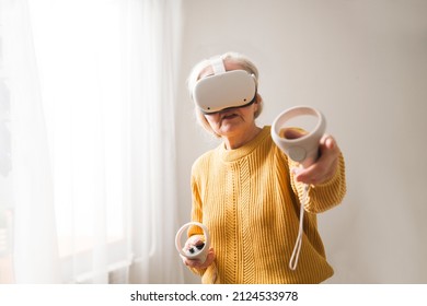  Virtual Reality. VR, Future, Gadgets. Senior Woman Playing Game In Virtual Reality Glasses And Holds Joysticks At Home