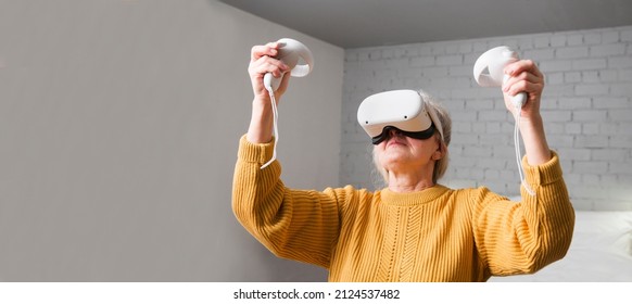  Virtual Reality. VR, Future, Gadgets. Senior Woman Playing Game In Virtual Reality Glasses And Holds Joysticks At Home