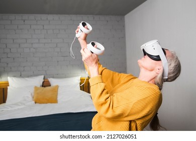  Virtual Reality. VR, Future, Gadgets. Senior Woman Playing Game In Virtual Reality Glasses And Holds Joysticks At Home