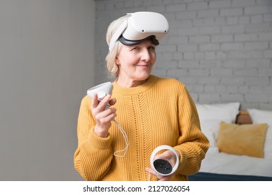  Virtual Reality. VR, Future, Gadgets. Senior Woman Playing Game In Virtual Reality Glasses And Holds Joysticks At Home