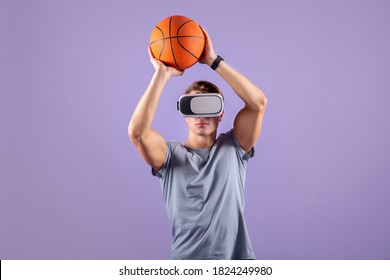 Virtual Sports Concept. Young Muscular Guy Playing Basketball While Wearing VR Headset On Violet Studio Background. Active Millennial Man Using Modern Technologies For His Workout