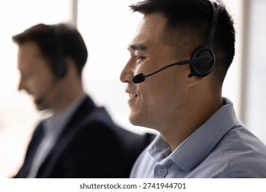 Virtual support. Head shot side portrait smiling young man hotline operator tech service agent in headphones with mic receive customer phone call give fast reliable assistance in modern service center