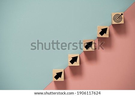 Virtual target board and arrow which print screen to wooden cube block on blue and pink background. Business achievement goal and objective target concept.