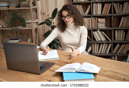 Virtual teaching concept. Female young hispanic school math teacher, college tutor coach looking at webcam and talking in classroom giving remote class online lesson by zoom conference call on laptop. - Shutterstock ID 1731088222