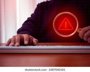 Virus alert. Red triangle icon, System hacked error sign, malware, attention danger symbol warning showing in magnifying glass lens, holding by businessman hand who working with computer in dark room. - Powered by Shutterstock