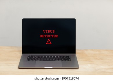 Virus dectected text and a caution warning sign in red popping up on a laptop screen. A hacked computer with bad security. Cybercrime, malware, ransomware