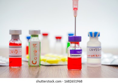 Virus And Recovery Concept, Close Up, There Are A Lot Of Vaccine Bottles With Red Or Green Liquid, Syringe And Pill Or Drug On Wooden Table