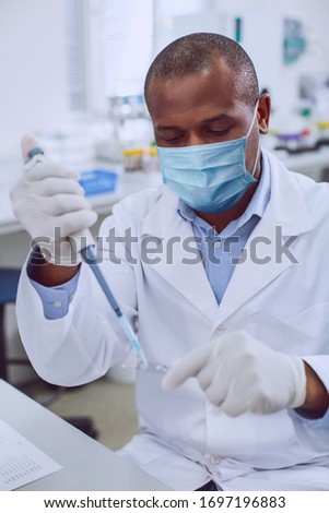 Virus testing. Professional lab worker holding a test sample while studying testing results